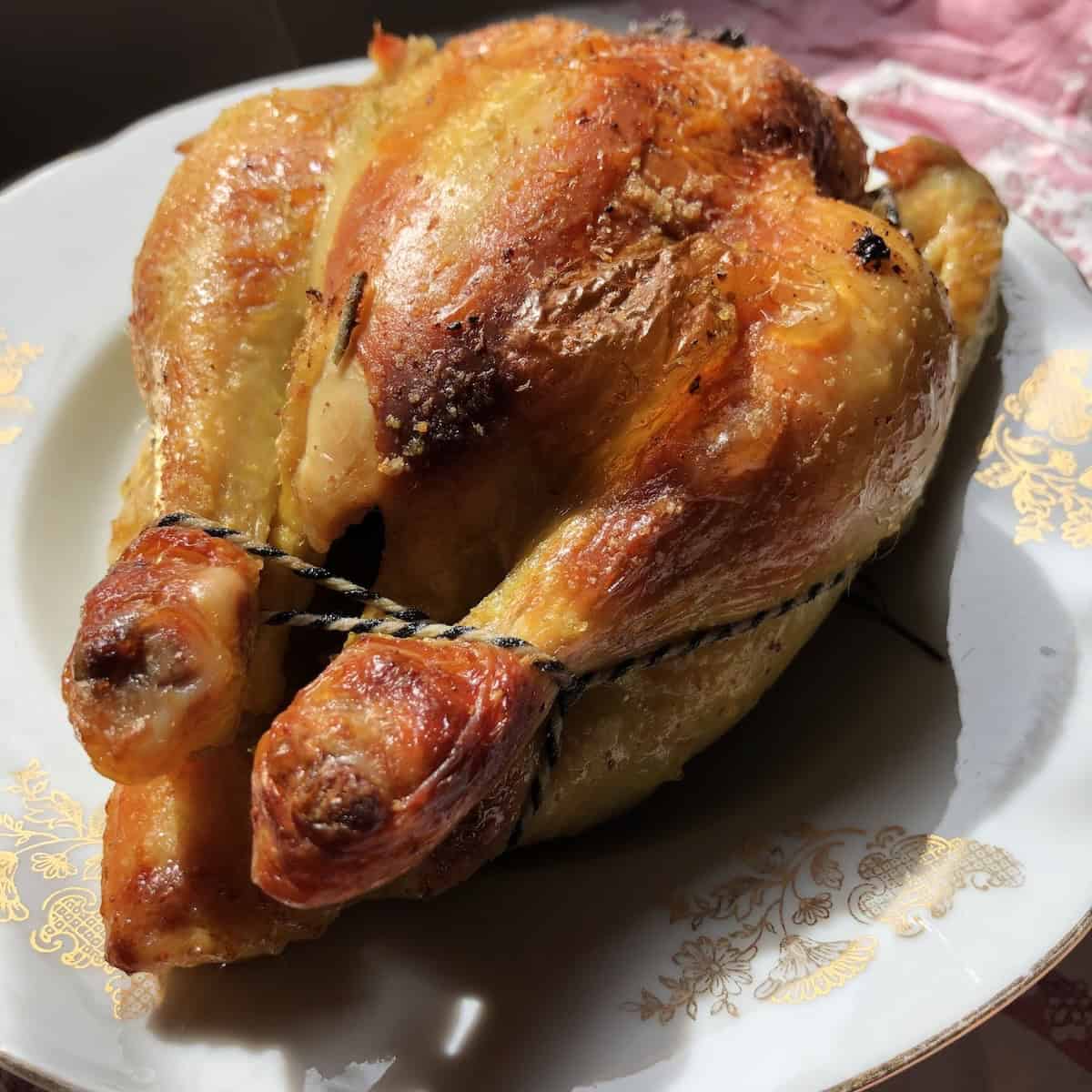 Homemade whole roasted chicken with golden brown crispy skin to use leftover bones for making homemade chicken stock recipe.