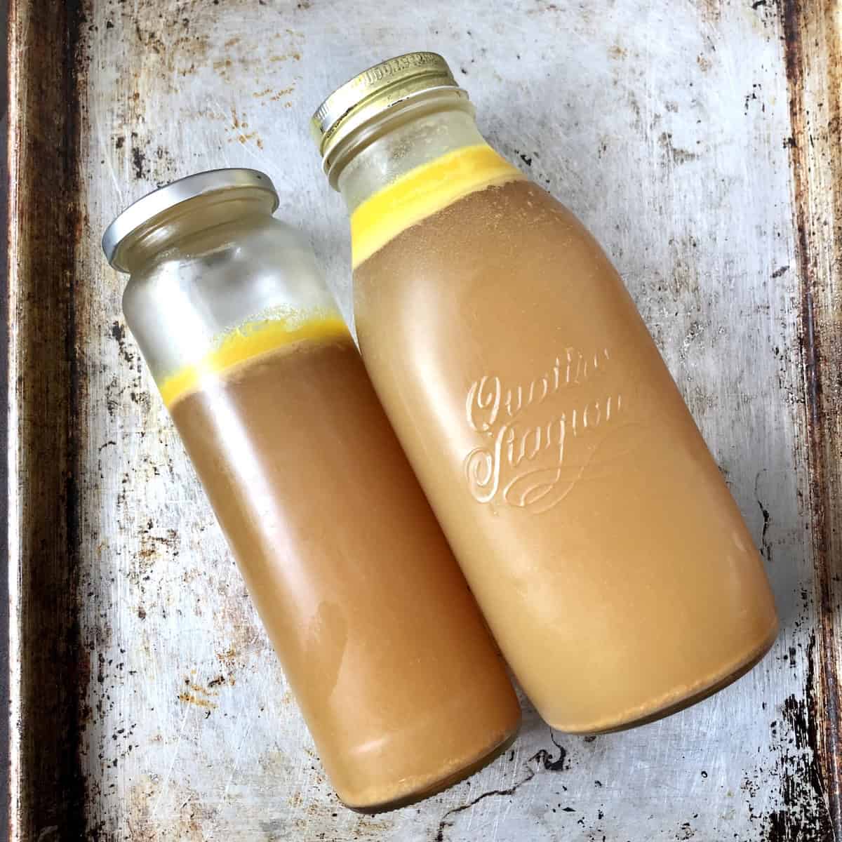 Three glass canning jars lying side by side showing gelatinous anti-inflammatory chicken bone broth with visible fat layer separation after refrigeration demonstrating perfect collagen rich homemade immune-boosting chicken bone broth texture.