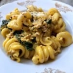 Creamy pumpkin pasta recipe served in a pasta plate topped with grated grana padano cheese, featuring sausage kale pasta in pumpkin pasta sauce.