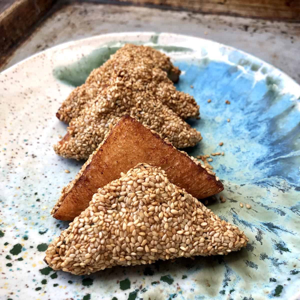 Just fried crispy golden shrimp toast on plate, perfect homemade Chinese shrimp toast appetizer with sesame seeds.
