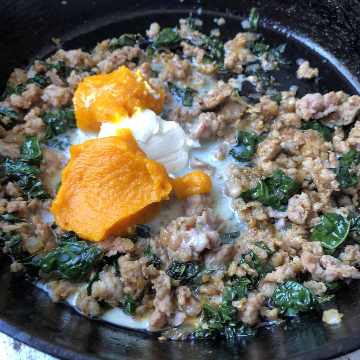 Adding pumpkin puree, heavy cream, and mascarpone to sausage kale mixture to make easy pumpkin pasta sauce.
