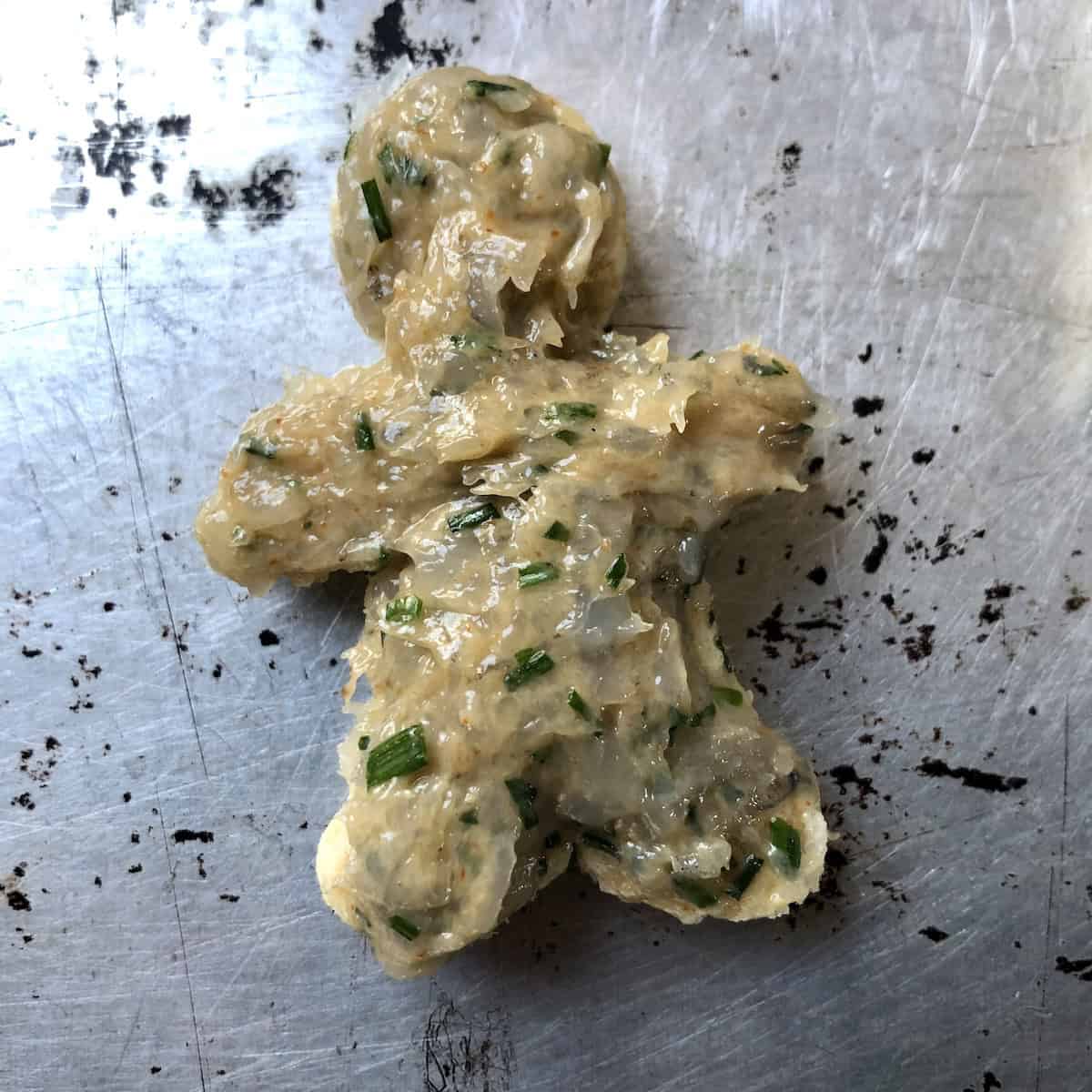 Gingerbread man shaped bread with shrimp paste filling spread on top before adding sesame seeds for a festive prawn toast appetizer for Christmas.