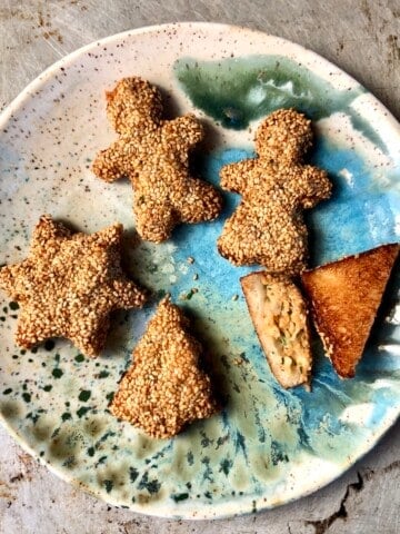 Platter of golden brown fried holiday shaped shrimp toasts including hearts, stars, Christmas trees, and gingerbread men for festive Chinese shrimp on toast appetizer.