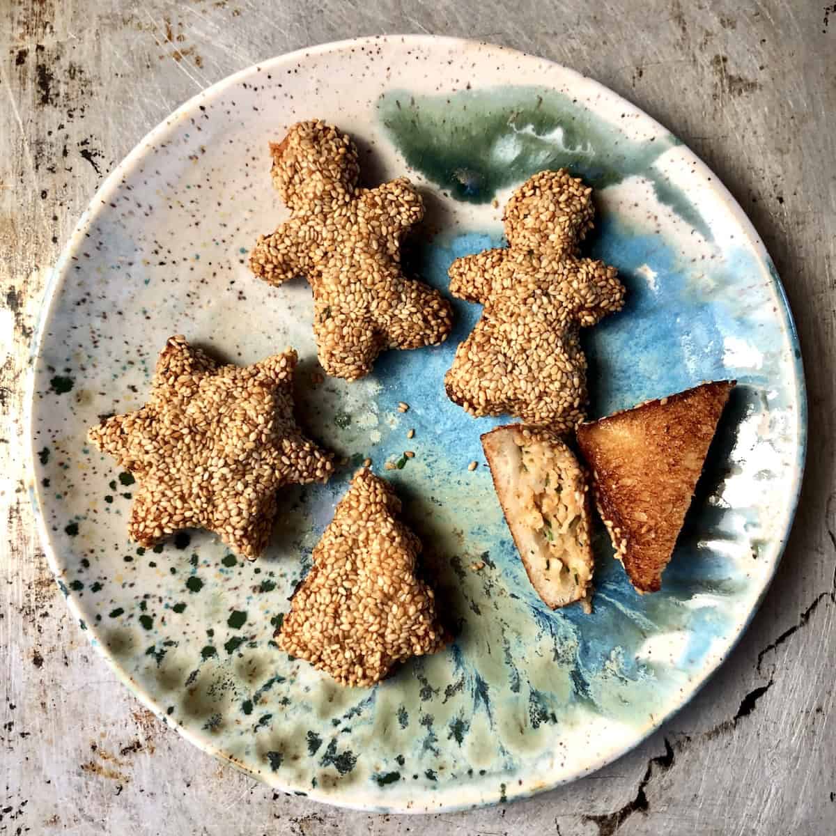 Platter of golden brown fried holiday shaped shrimp toasts including hearts, stars, Christmas trees, and gingerbread men for festive Chinese shrimp on toast appetizer.
