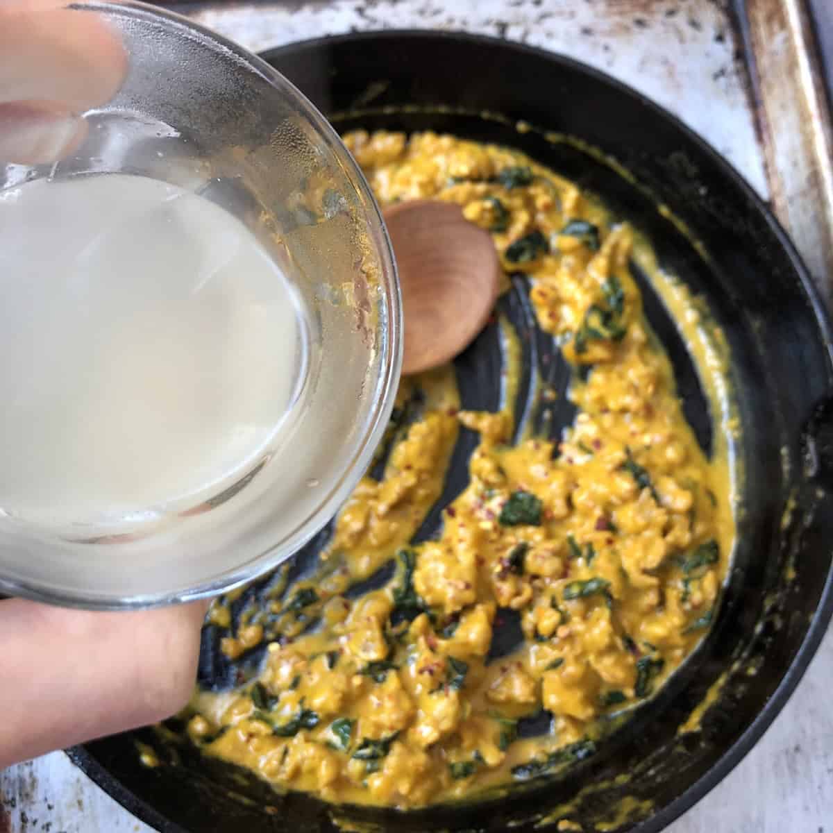 Adding starchy pasta cooking water to pumpkin cream sauce to loosen the creamy pumpkin pasta sauce.
