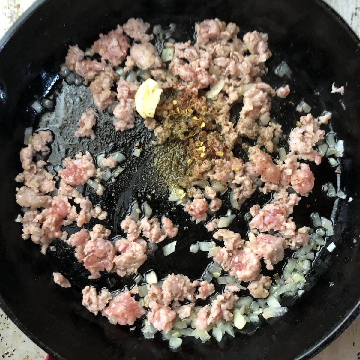 Italian sausage and onions cooking in a skillet for pumpkin sausage pasta, building the base for creamy pumpkin pasta sauce.
