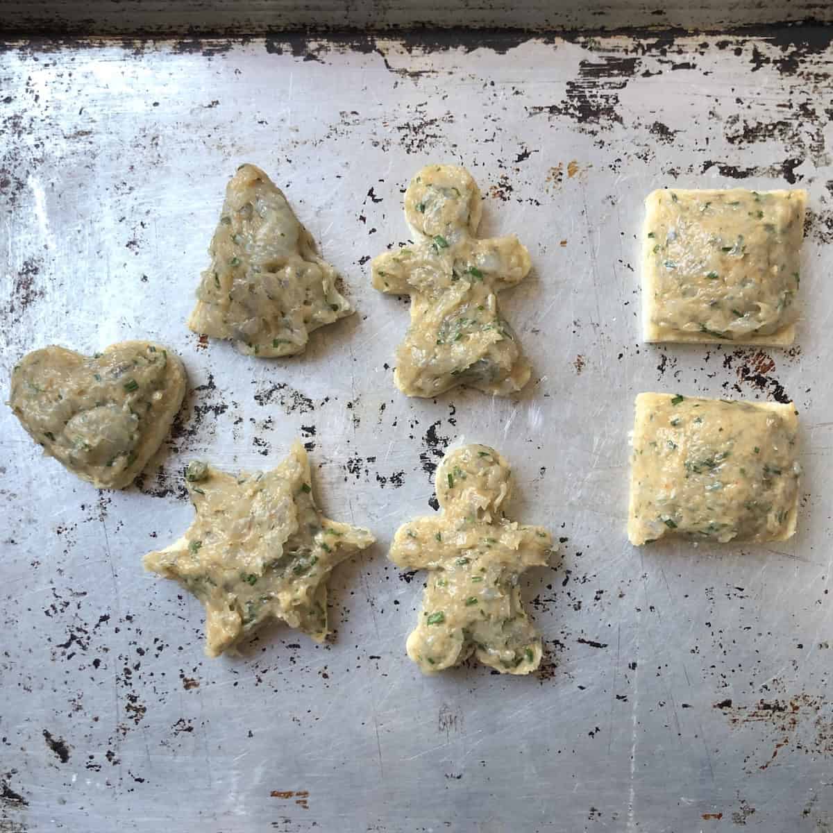 Platter of holiday shaped shrimp toasts including hearts, stars, Christmas trees, gingerbread men, squares, and triangles before adding sesame seeds for festive Chinese shrimp toast appetizer.