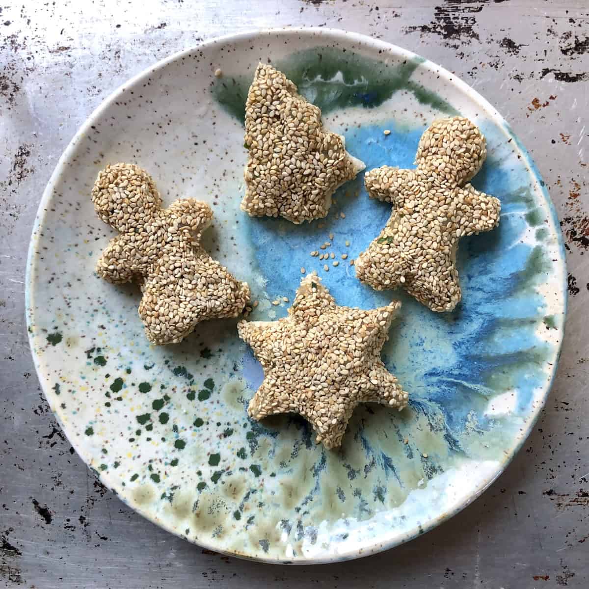Two gingerbread men, Christmas tree, and star shaped shrimp toasts with sesame seeds fully assembled and ready to fry for holiday prawn toast appetizer.
