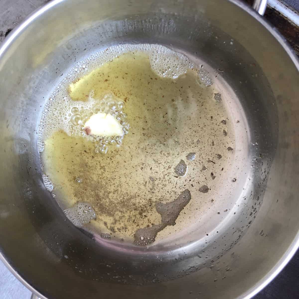 Blistering garlic in clarified butter to perfume the fat before cooking shrimp for lobster ravioli filling shrimp mousse.
