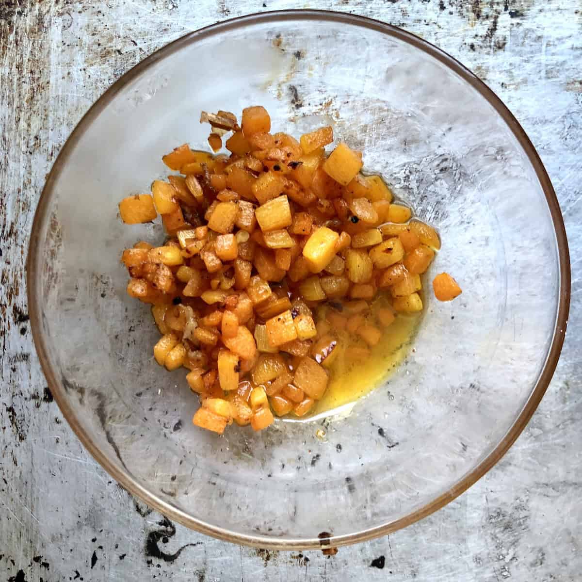 Caramelized carrots deglazed with white wine cooling in a prep bowl for homemade lobster ravioli filling.
