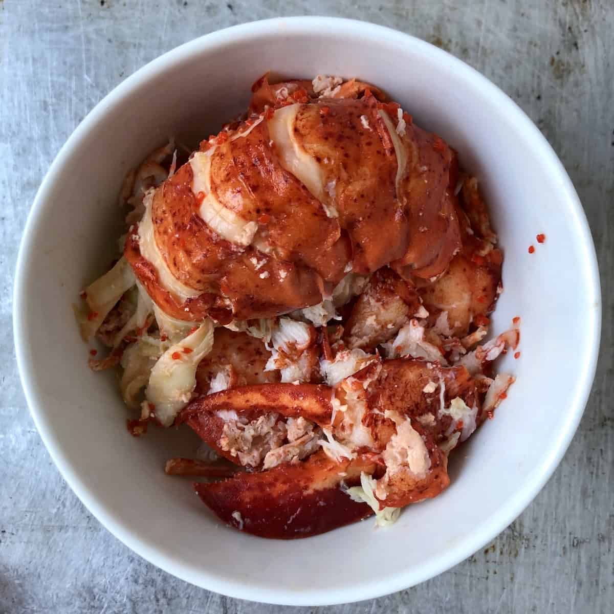 Cooked lobster meat in a bowl ready to be diced for homemade lobster ravioli filling.
