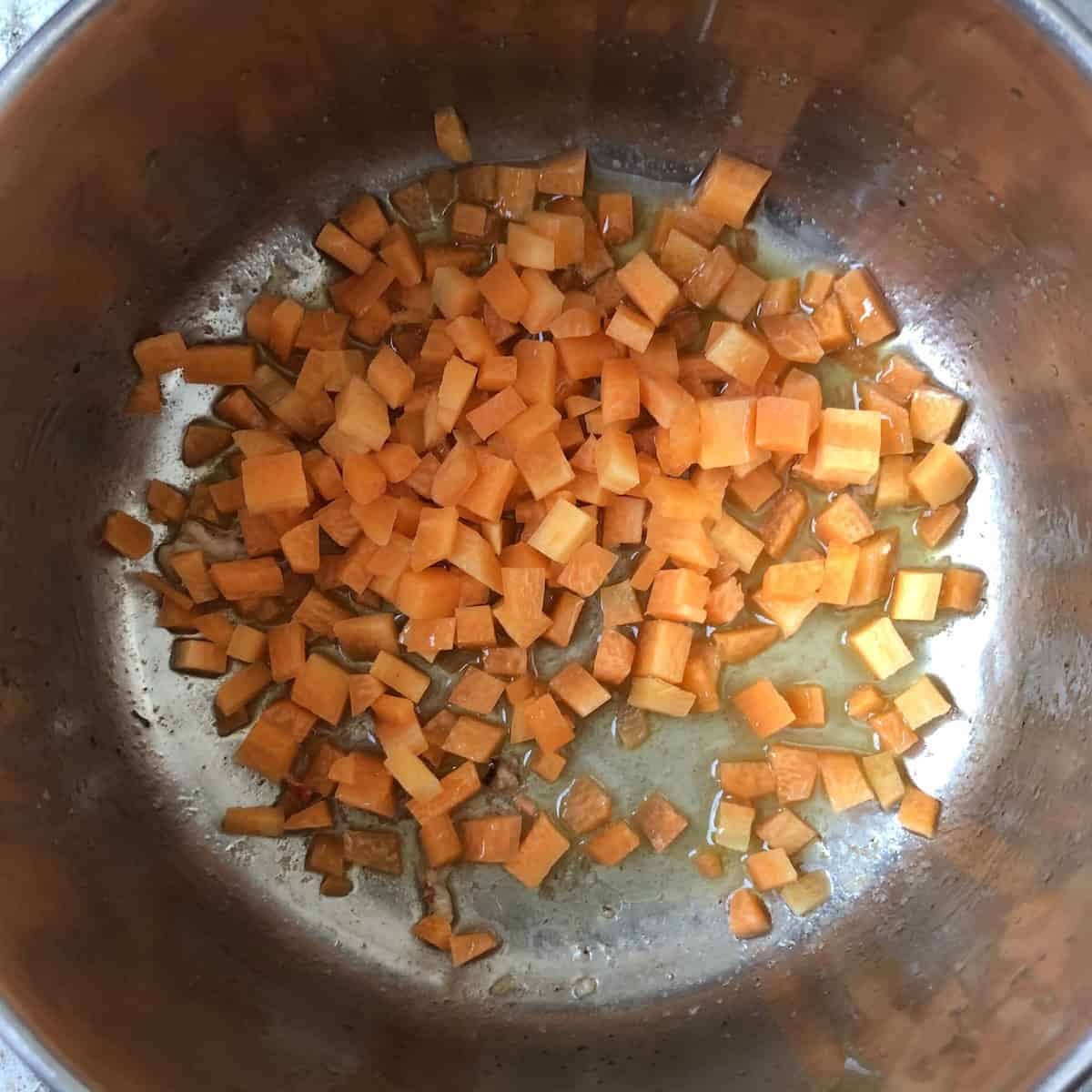 Raw diced carrots added to clarified butter mixture to cook until caramelized for lobster ravioli filling.
