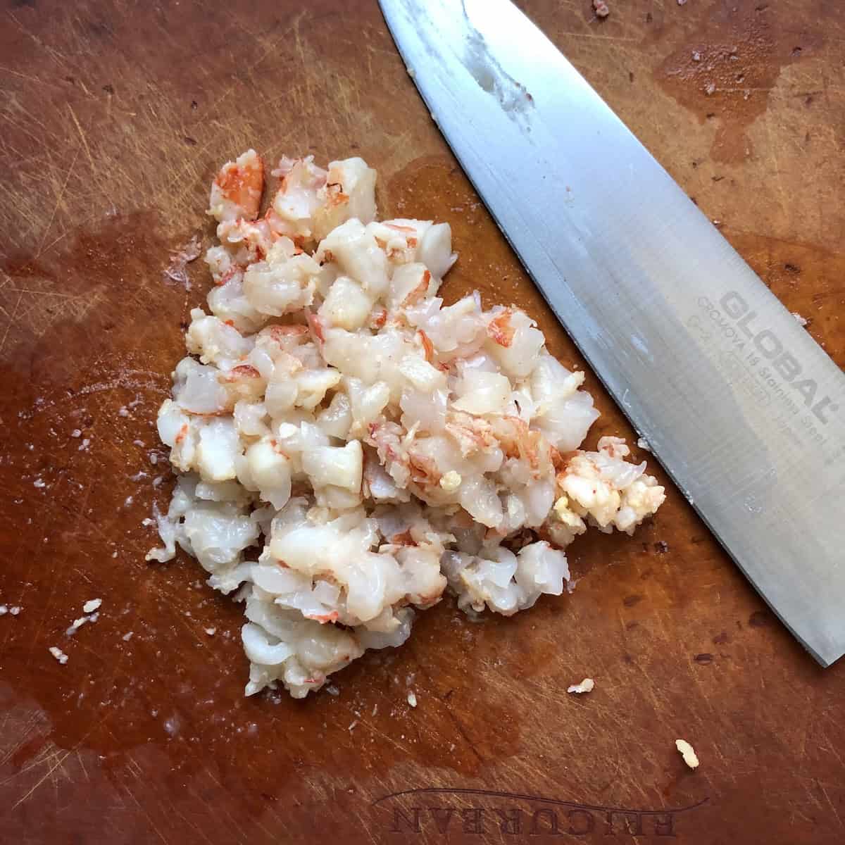 Remaining par-cooked Argentinian red shrimp diced on a cutting board to add texture to lobster ravioli filling.
