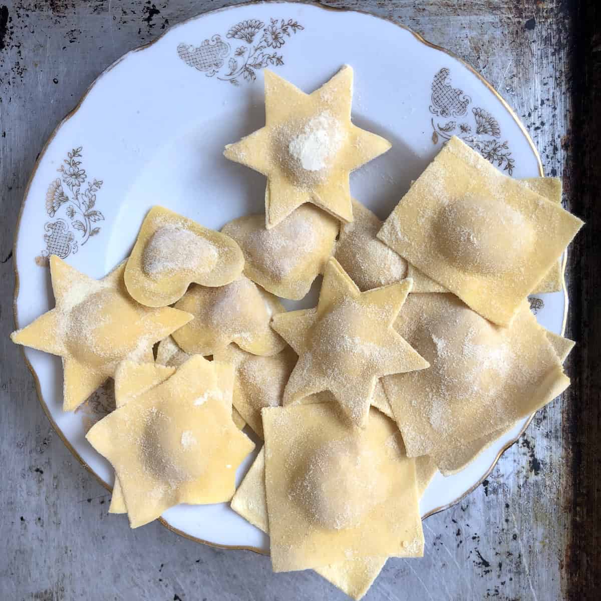 Heart shaped and star shaped homemade lobster ravioli on a plate ready to cook or freeze for meal prep, ravioli shapes for lobster ravioli recipe.