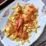 Homemade lobster ravioli and shrimp ravioli in heart and star shapes on a serving platter covered with lobster tomato cream sauce, showing the best sauce for lobster ravioli recipe.