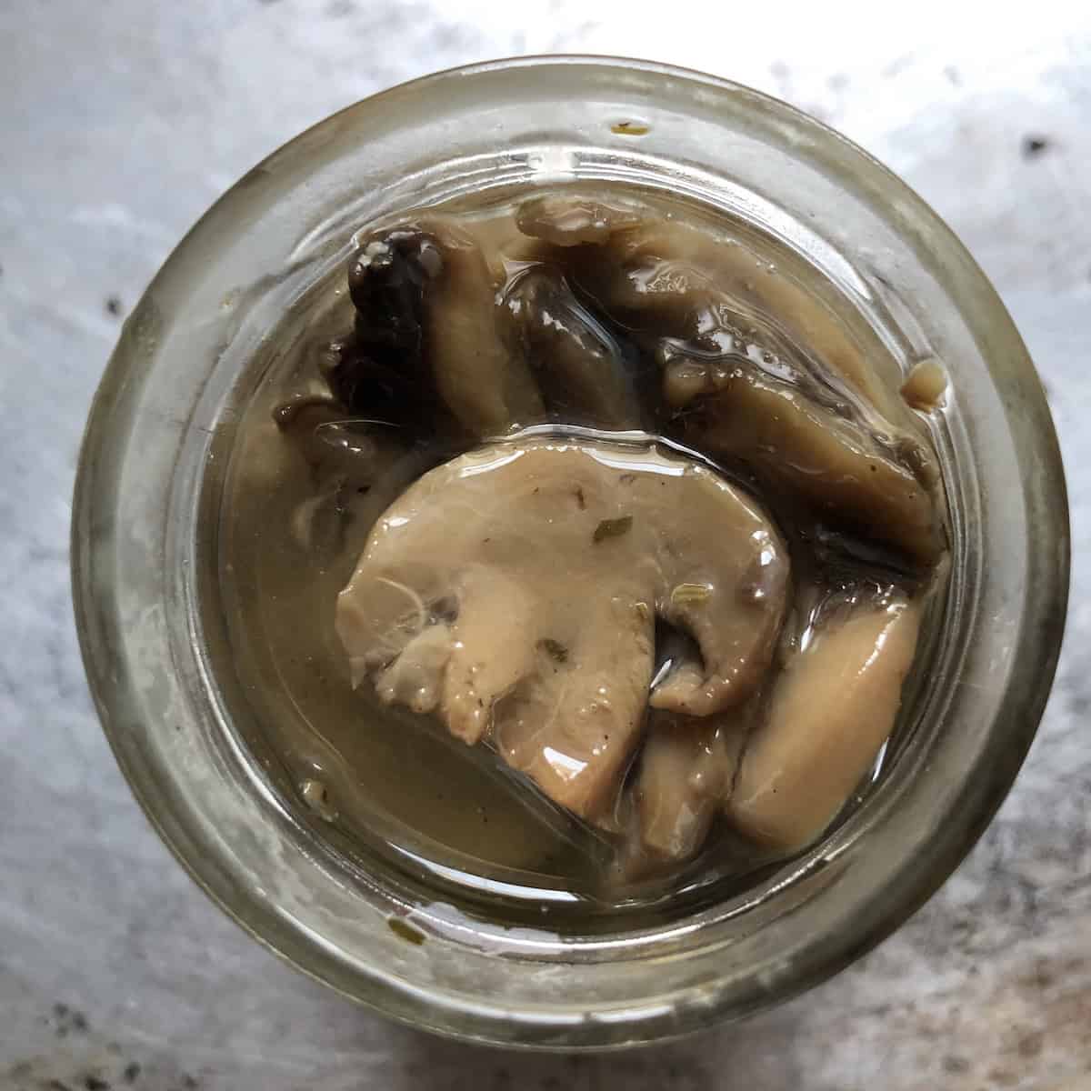 Top down view of seasoned Italian mushrooms in oil, a popular shortcut for authentic pasta ai funghi that many Italian home cooks use instead of fresh mushrooms for easy mushroom pasta.
