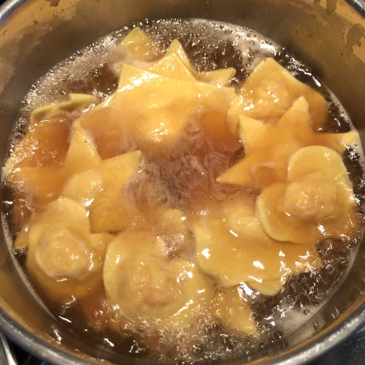 Homemade lobster ravioli cooking in salted homemade seafood stock for the best lobster ravioli recipe.