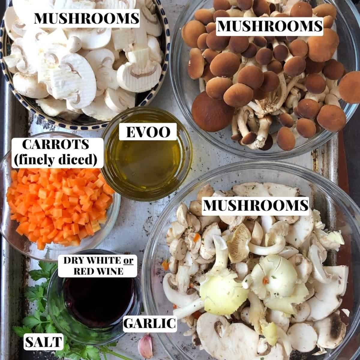 Ingredients for pasta ai funghi on a sheet pan including fresh mushrooms, tagliatelle, garlic, carrots, olive oil, parsley, and Grana Padano for authentic Italian mushroom pasta.
