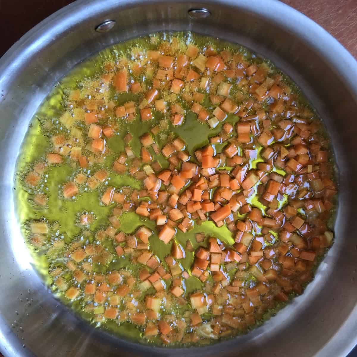 Finely diced carrots added to garlic and olive oil for mushroom pasta sauce, a simple addition that adds natural sweetness and a ton of extra flavor.
