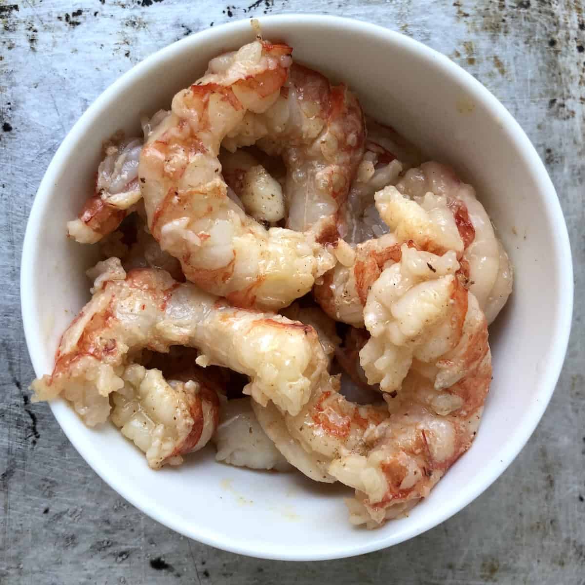 Parcooked shrimp in a bowl ready to cool and refrigerate before making shrimp mousse for homemade lobster ravioli filling.
