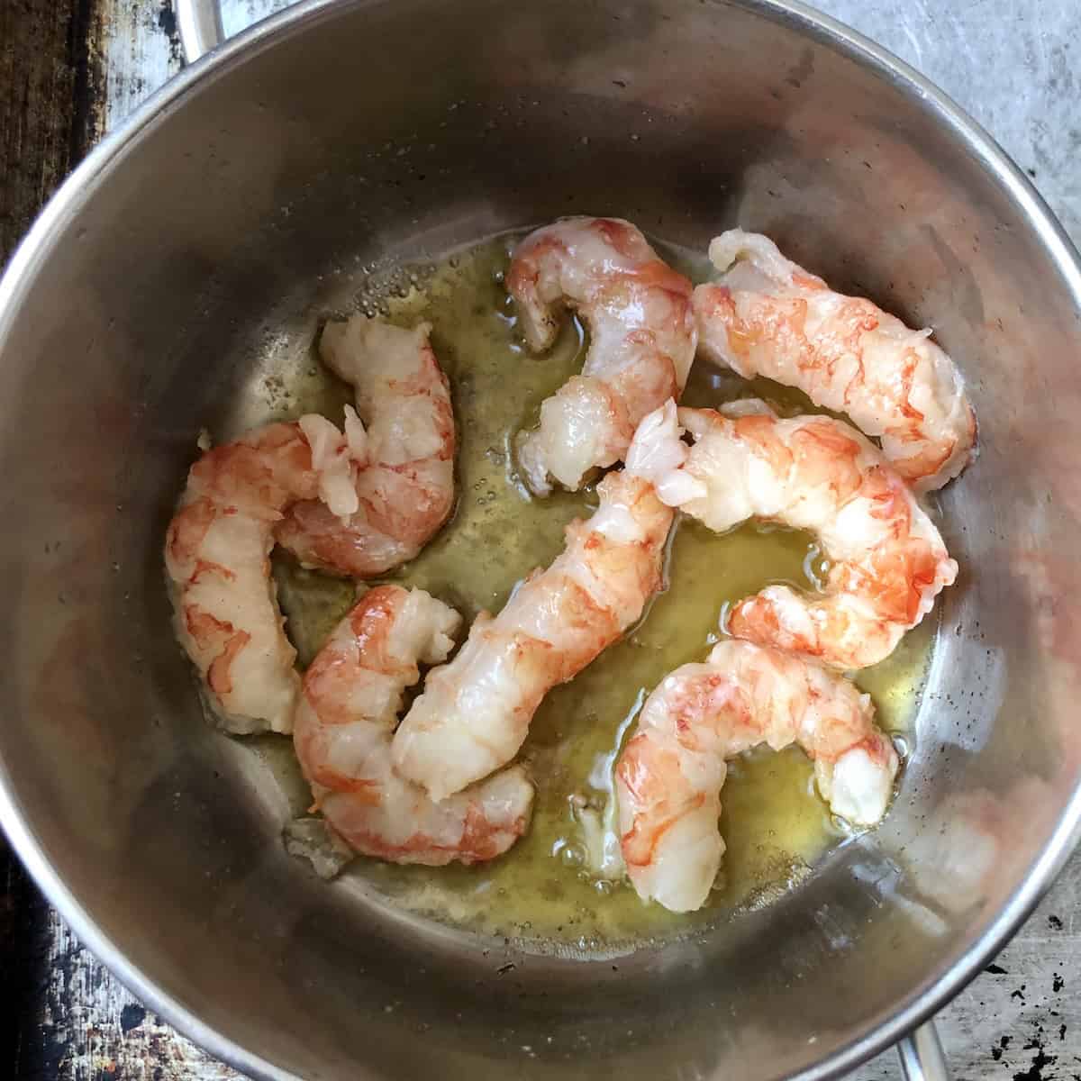 Parcooking Argentinian red shrimp for 30 seconds per side in garlic infused clarified butter for lobster ravioli filling shrimp mousse.
