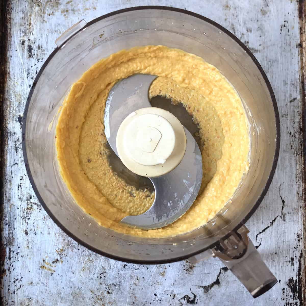 Pureed light orange creamy carrot and cheese mixture in food processor for homemade lobster ravioli filling.
