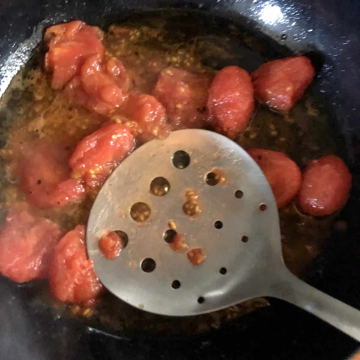Smashing grape tomatoes and cooking for a few minutes for homemade lobster ravioli tomato cream sauce.
