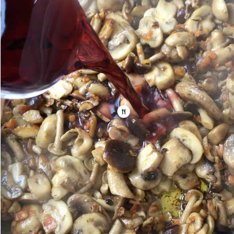 Adding wine to deglaze the pan of sautéed mushrooms, building flavor for pasta with mushrooms Italian style.
