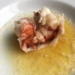 A perfectly boiled lobster tail sitting in a pool of warm clarified butter, showing the bright red and white tender lobster meat. An easy and elegant lenten seafood dinner in just 4 minutes.