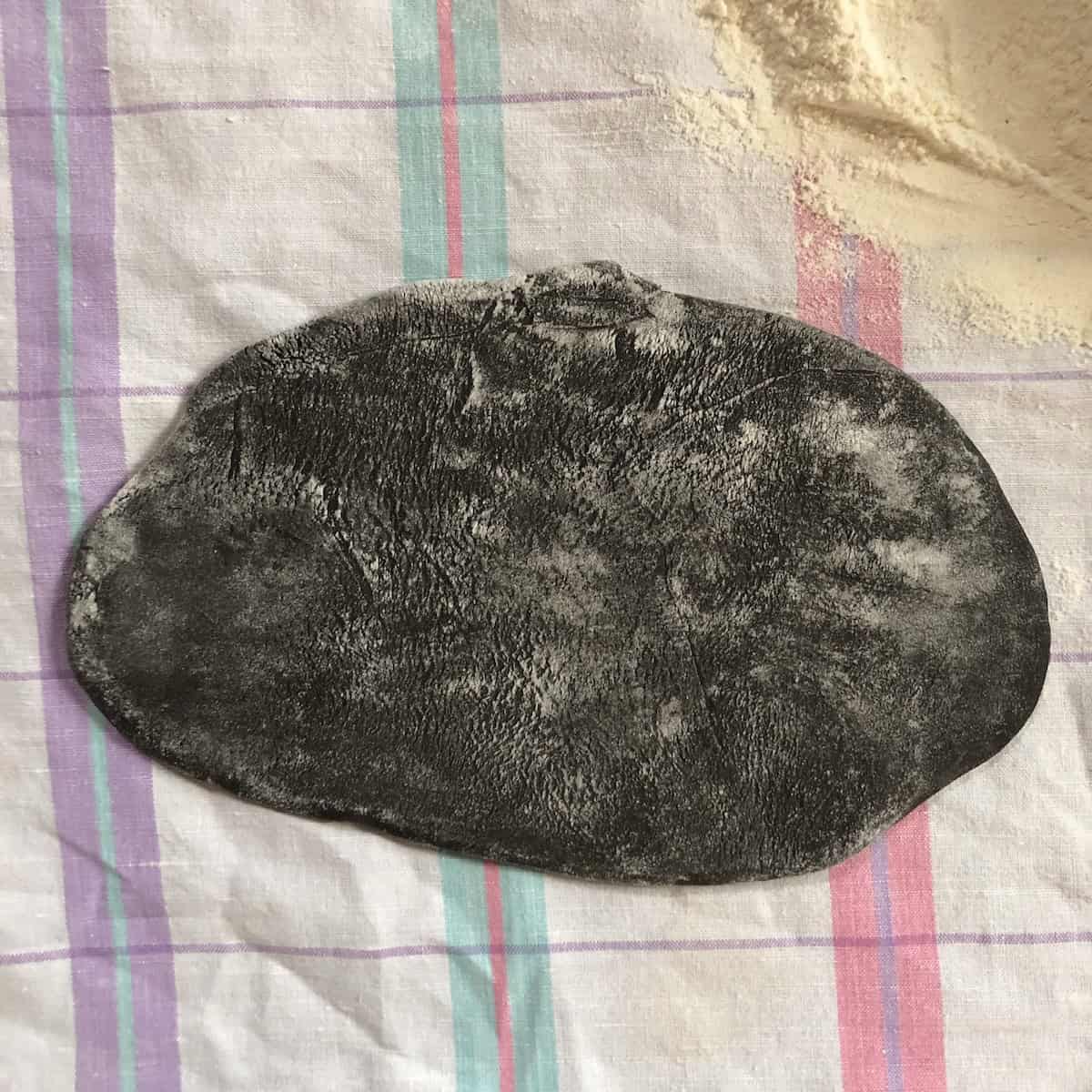 Black pasta put through the pasta machine looking flatter and wide, now ready for the business letter fold and one more time on the widest pasta machine setting.
