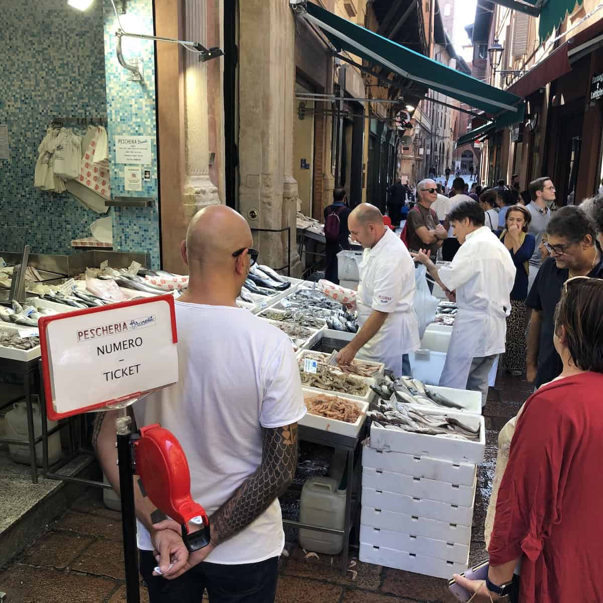 Bologna Italy fish market on Via Pescherie Vecchie showing ticker number system for buying fresh seppia cuttlefish, squid, and seafood from Italian fishmonger.

At Pescheria Brunelli, Via Drapperie, 8a, 40124 Bologna BO, Italy
