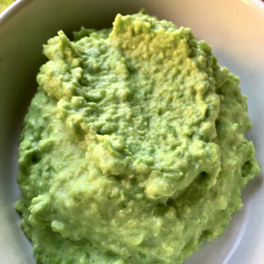 A mini casserole dish filled with creamy mushy peas showing the thick, buttery texture and bright green color. An easy lenten side dish ready in minutes.