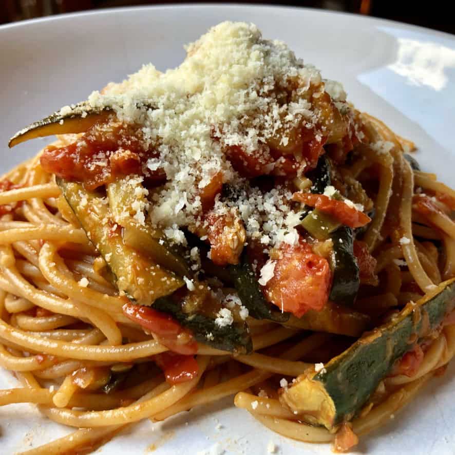 Italian spaghetti with zucchini and fresh tomatoes tossed with garlic and Parmigiano-Reggiano cheese in a white pasta bowl. A quick meatless lenten pasta recipe ready in under 20 minutes.