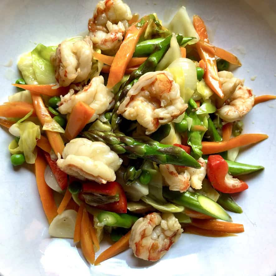 Shrimp and vegetable stir fry in a light Cantonese white sauce with sauteed shrimp, carrots, asparagus spears, cabbage, and peas in a serving bowl. An easy and healthy lenten Asian seafood dinner.