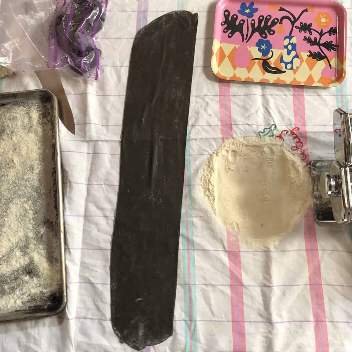 Long sheet of black squid ink pasta ready to cut into fettuccine, linguine, spaghetti, pappardelle, tagliatelle, or used for black lasagna noodles or black ravioli for this cuttlefish ink pasta recipe.

