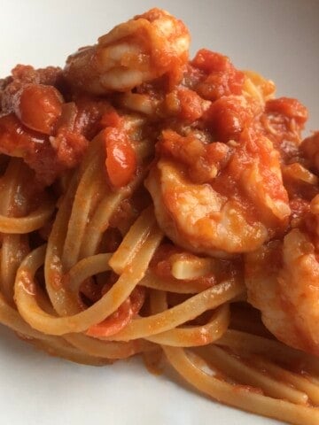 Naturally creamy triple shrimp pasta made without cream, featuring trighetto pasta in a rich tomato shrimp sauce that uses all parts of the shrimp including the heads to flavor the pasta in a deep pasta bowl. A decadent lenten seafood pasta recipe.