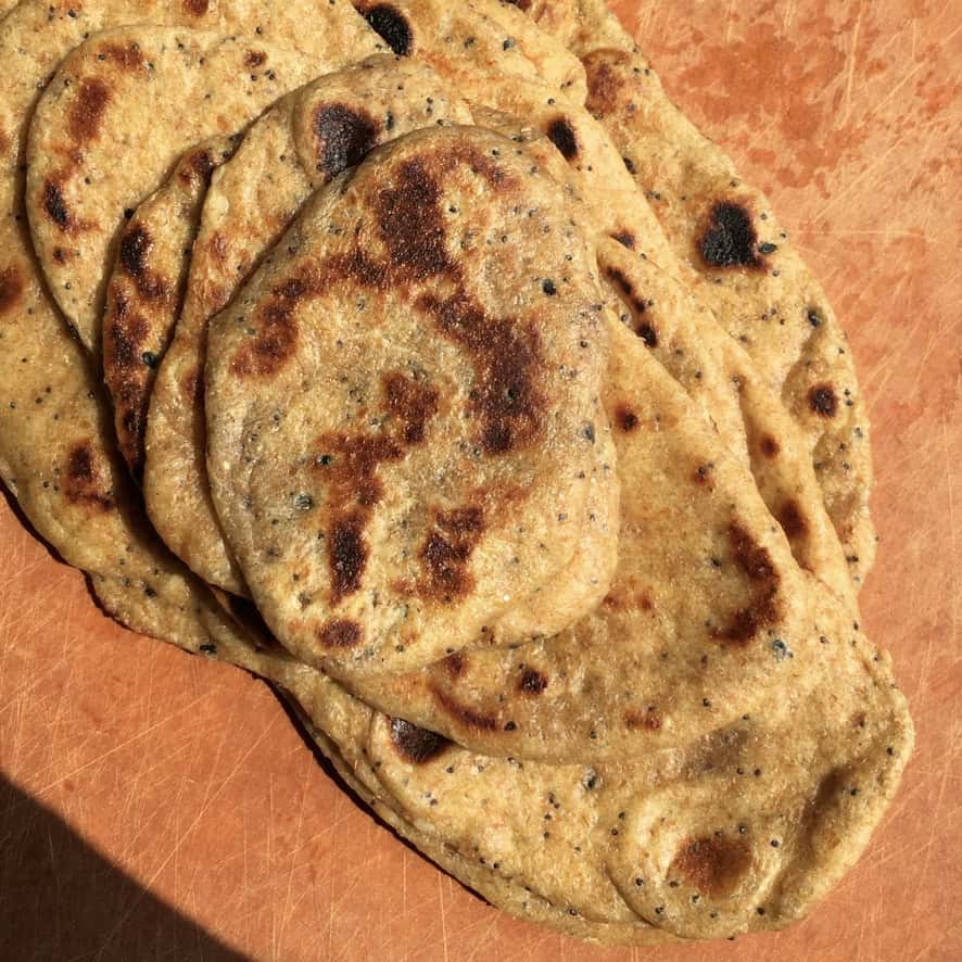 A stack of whole wheat everything bagel seasoned naan bread topped with sesame seeds, poppy seeds, dried garlic, and onion flakes. A flavorful twist on homemade naan for lenten dipping and snacking.
