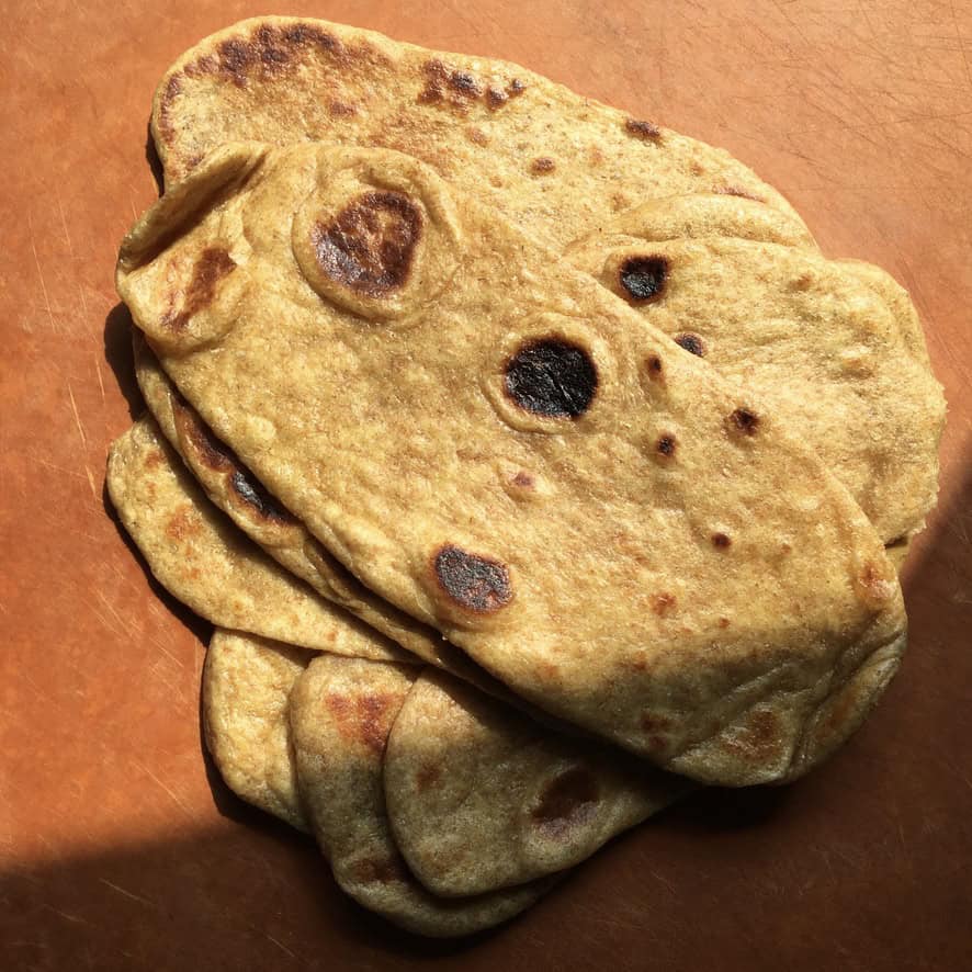 A stack of super fluffy whole wheat naan bread showing soft pillowy layers with golden brown spots. A healthier homemade naan perfect for pairing with hummus and soups during Lent.