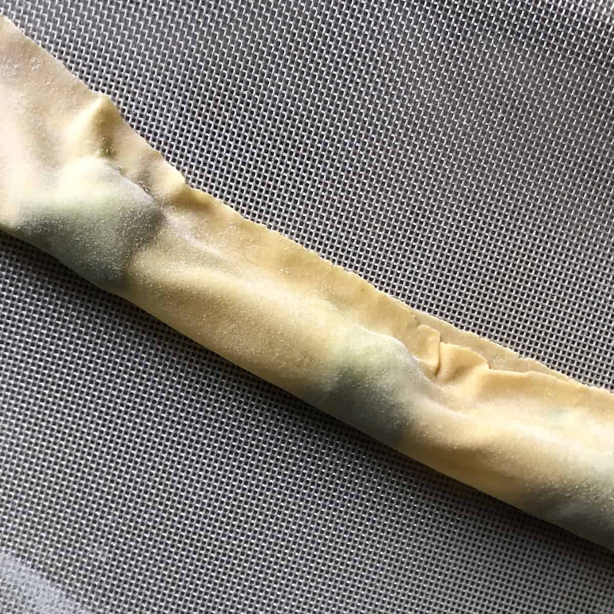 Fresh pasta dough folded over to enclose the spinach and ricotta filling, ready to be pressed and sealed into fresh ravioli.