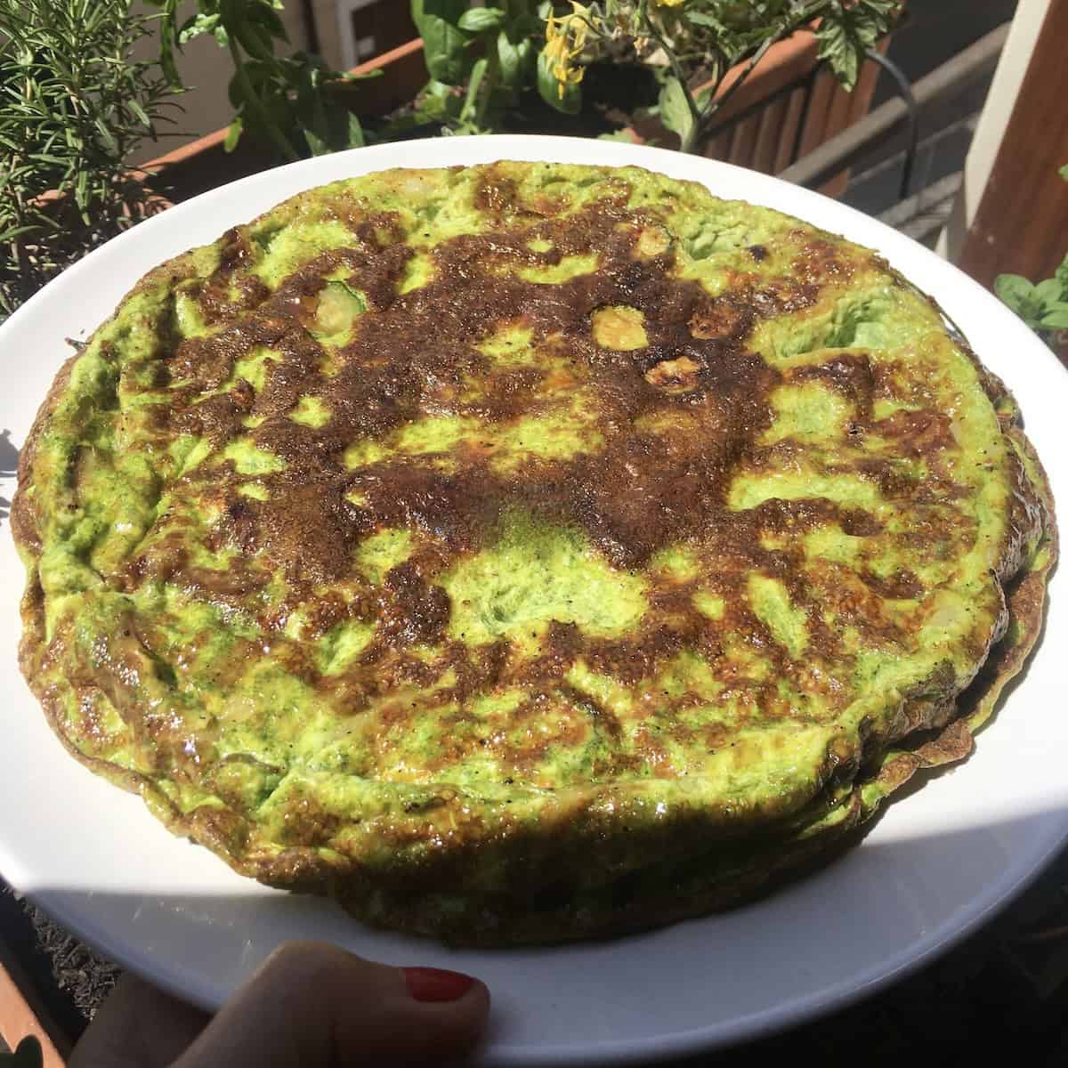 Asparagus and zucchini frittata with golden brown top covered in grated parmesan cheese, savory brunch recipes and brunch food ideas for a crowd.