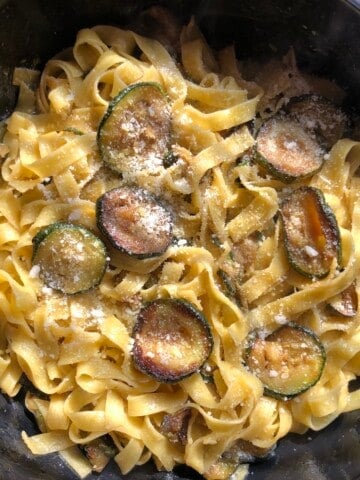 A skillet full of homemade pasta alle zucchine (or better known as pasta with zucchini with tagliatelle standing in for spaghetti and sprinkled with a handful of freshly grated aged Grana Padano cheese.