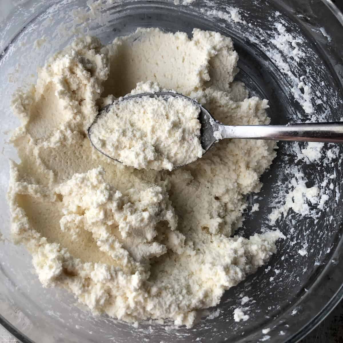 The combined ricotta, mascarpone, Grana Padano, and spice mixture beaten stiff in a mixing bowl, ready for the garlic paste and chopped spinach to be folded in for the spinach and ricotta ravioli filling.