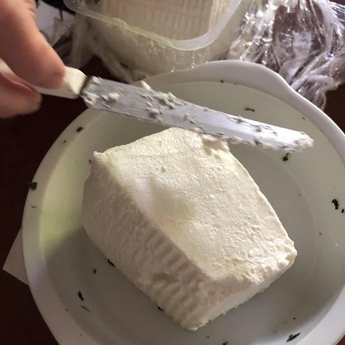 A wedge of fresh strained ricotta from a Northern Italian cheese counter - the authentic ingredient choice over plastic tub ricotta for a traditional ravioli recipe filling.