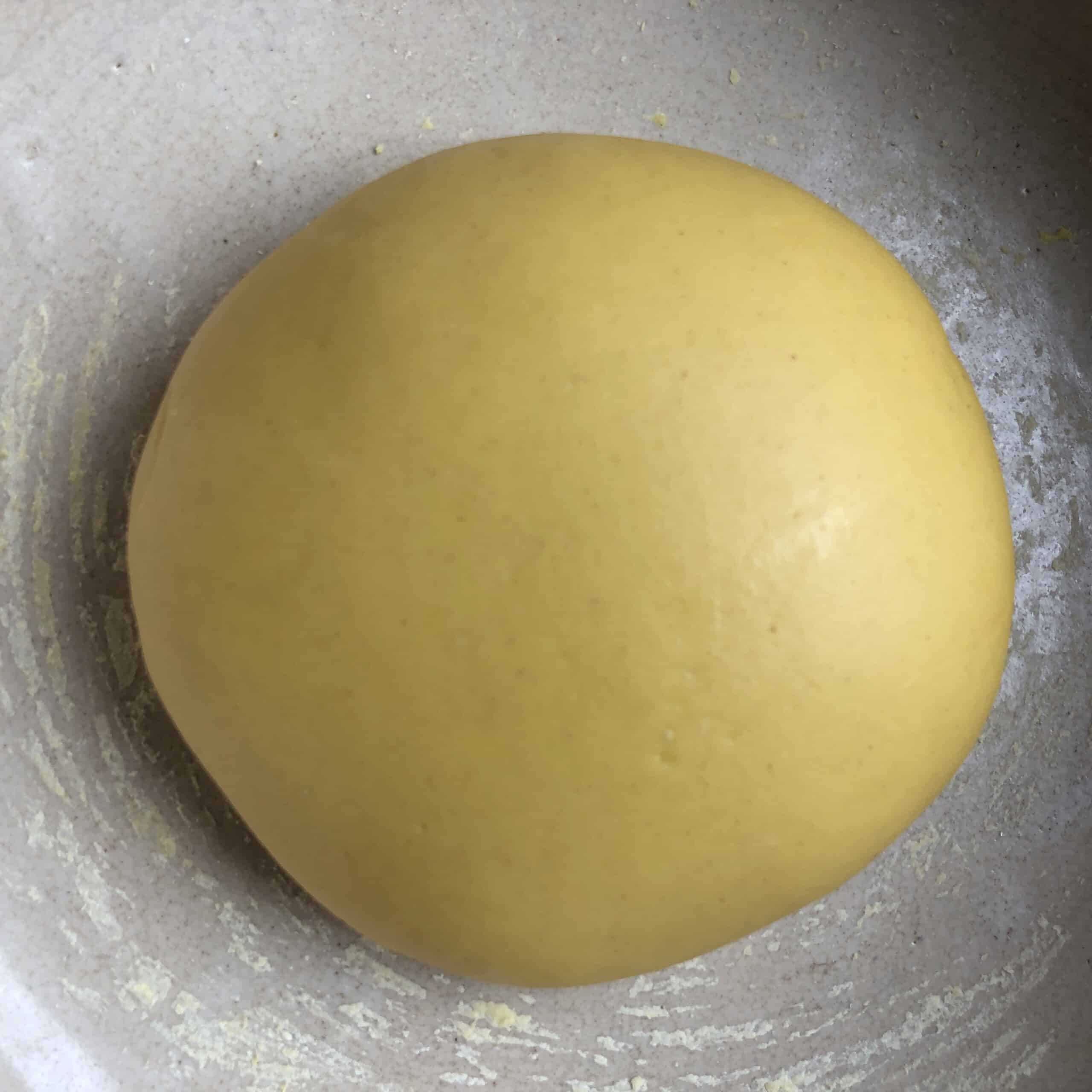 A rested half twice-milled semolina and 00 flour pasta dough ball in a vintage bread bowl, ready to be rolled out for a ravioli from scratch recipe.