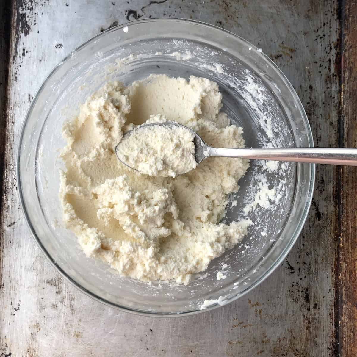 Properly strained ricotta cheese showing a firm, sturdy texture - the correct consistency for a homemade ravioli filling that holds its shape inside fresh pasta when you're not using an egg as a binder .
