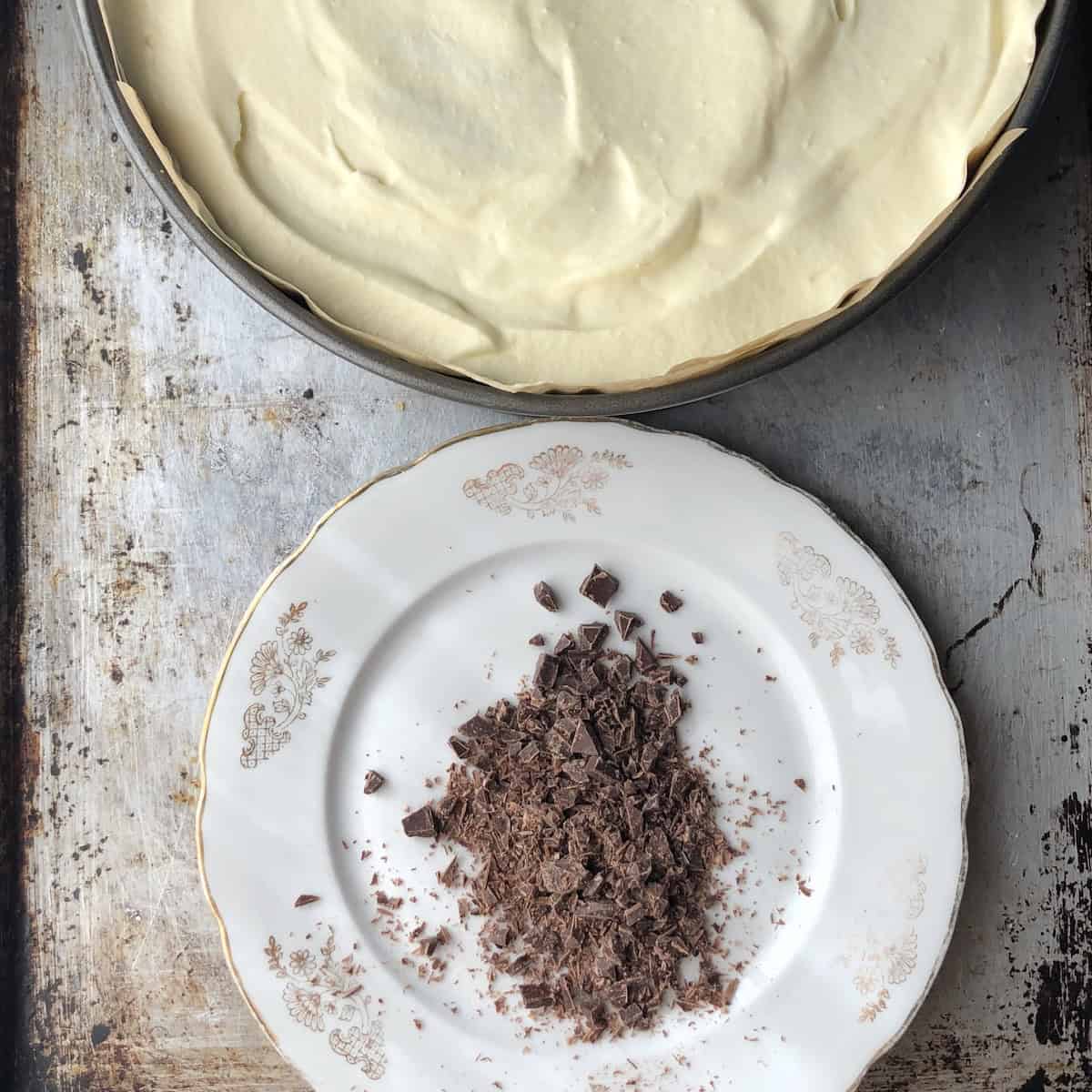 Tiramisu refrigerated overnight still in the springform pan with chopped 78 percent Lindt dark chocolate on a plate as optional topping.
