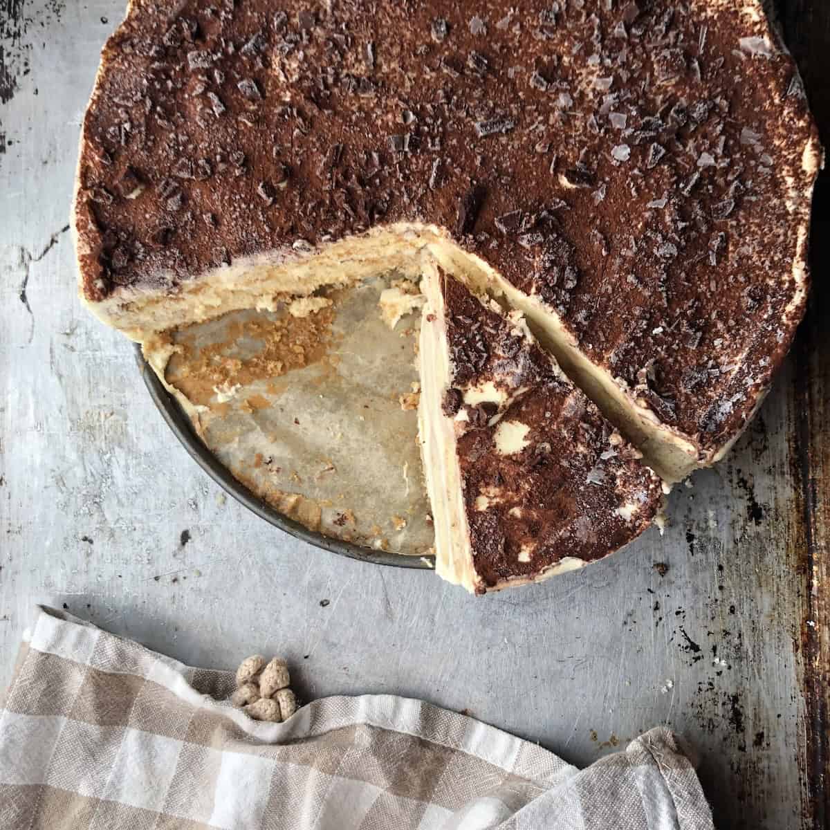 Whole frozen tiramisu with a slice removed showing frost on top of the dessert, freezer friendly Italian tiramisu.