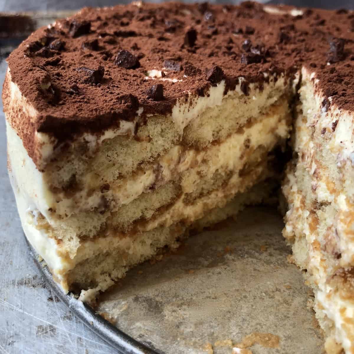 Interior view of whole tiramisu with three layers of mascarpone cream and espresso soaked ladyfingers, perfectly set and fluffy.