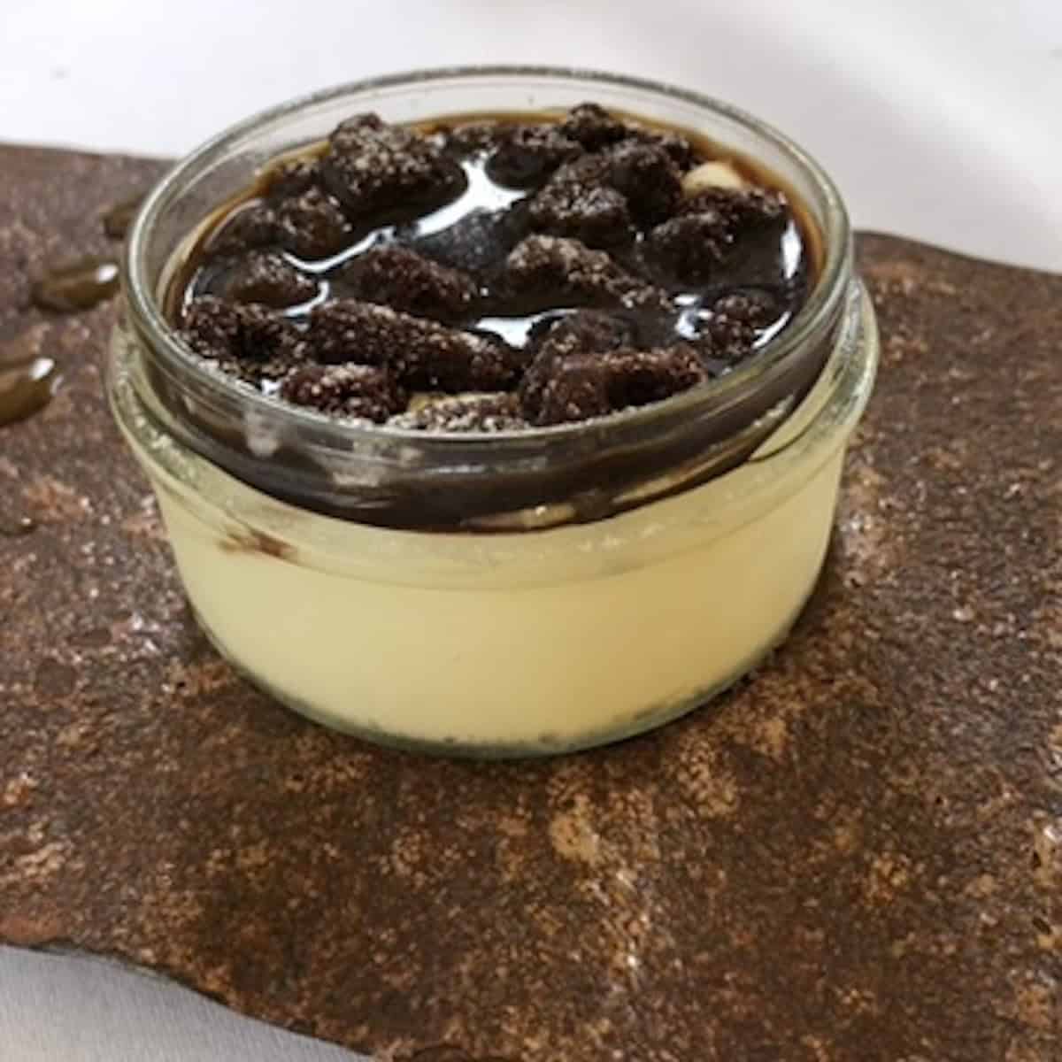 Side view of fine dining tiramisu with espresso poured on top, showing layers through the glass jar, Italian tiramisu italiano.

