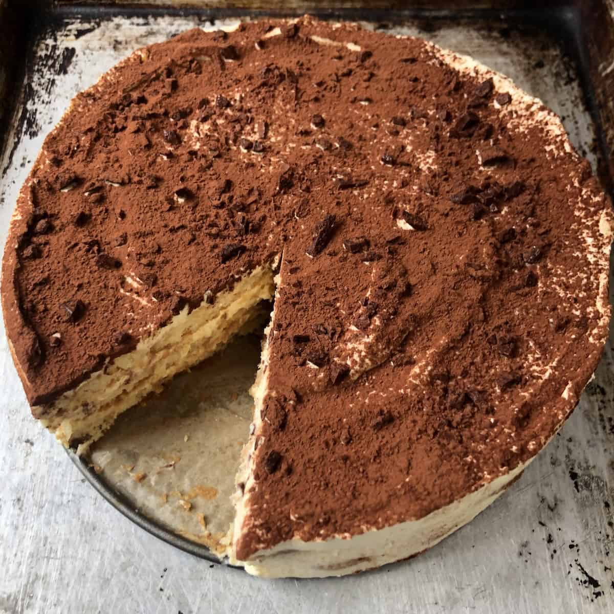 Full homemade tiramisu with chopped dark chocolate and cocoa powder on top using the clean sides layering method for a professional finish.